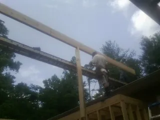 Carpenter setting a ridge beam over a new addition frame — Ice Dam Removal by Roofing Brothers in Berry