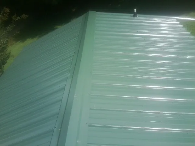 New green metal panels meeting at the ridge of a roof — Flat Roof Repair work by our crew in Berry