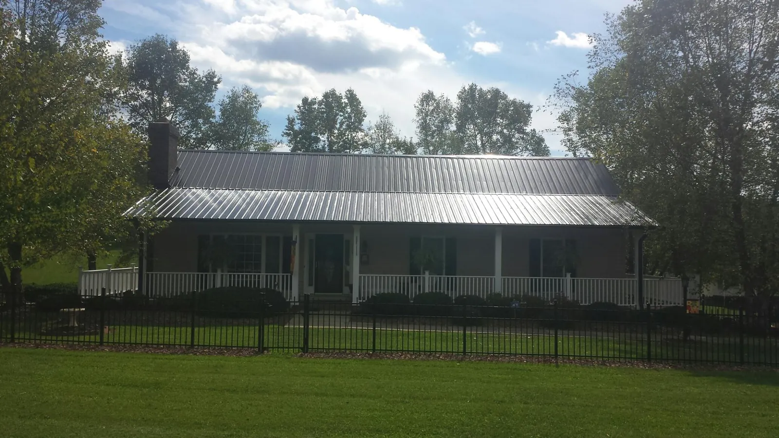 Gray metal roof on a brick ranch with a full width front porch — Gutter Guard Installation work by our crew in Berry