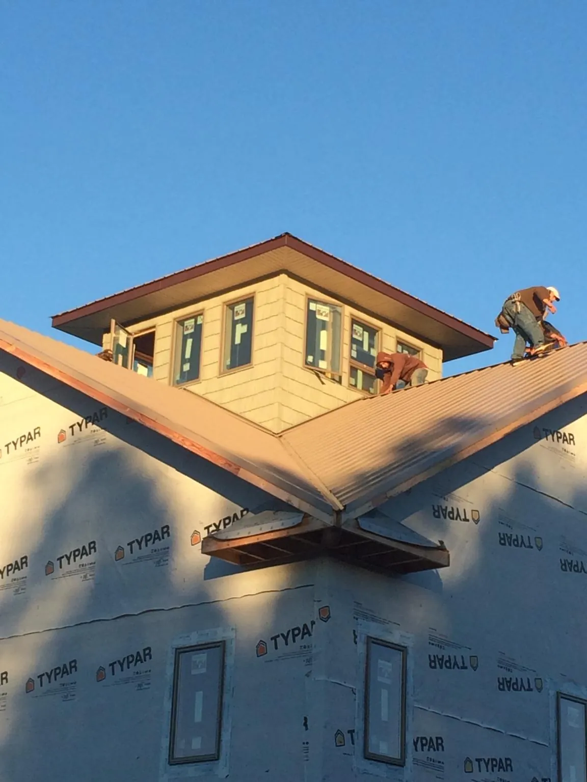Roofers working around a rooftop cupola on a new metal roof at sunset — Roof Waterproofing in Berry by Roofing Brothers